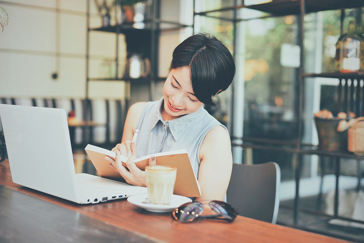 Woman-smiling-while-writing-in-an-agenda